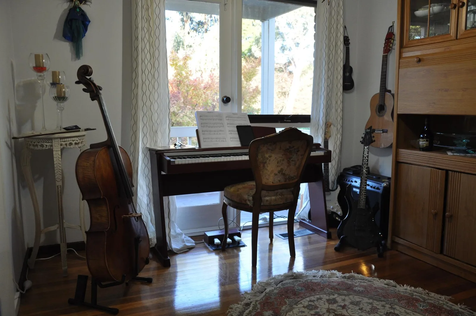 A childhood music room with piano, cello and guitars by a window.
