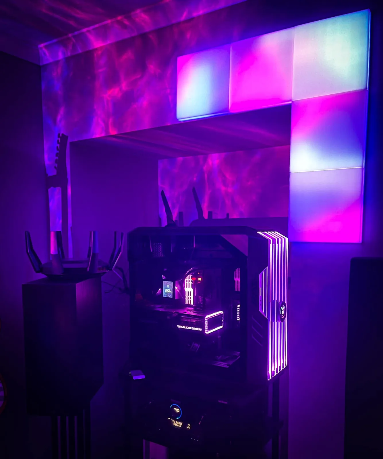 An RGB gaming PC beside a wall of light panels.