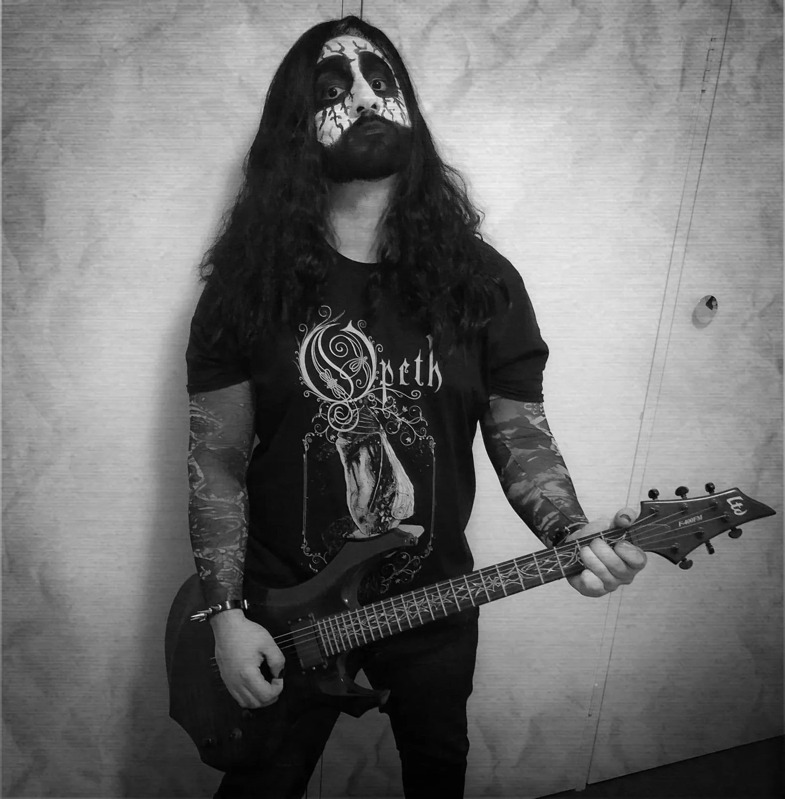 Arman in black-metal corpse paint holding a guitar.