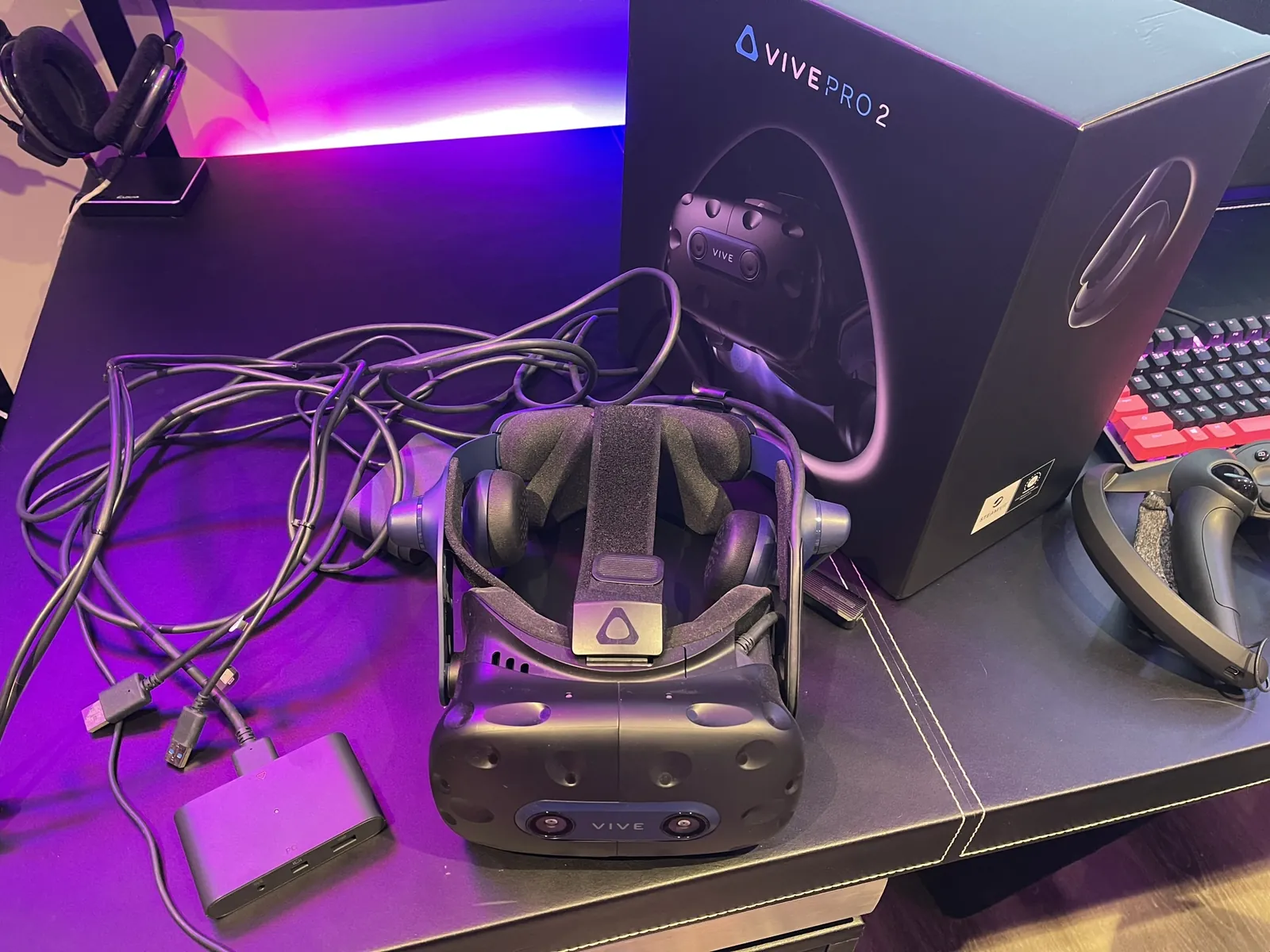 Vive Pro 2 headset unboxed on a desk under purple light.