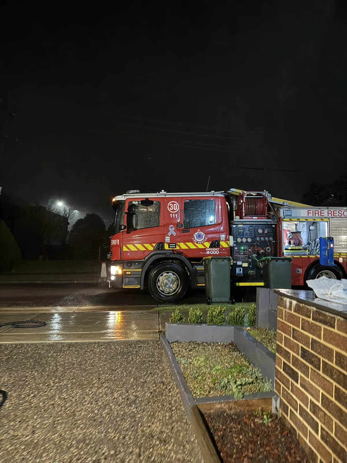 A fire truck working a flooded suburban street at night.