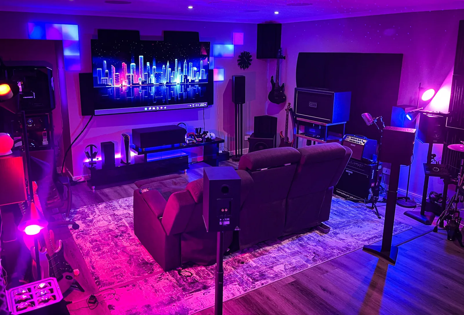 The original room glowing purple: screen, speakers, guitars, recliners.