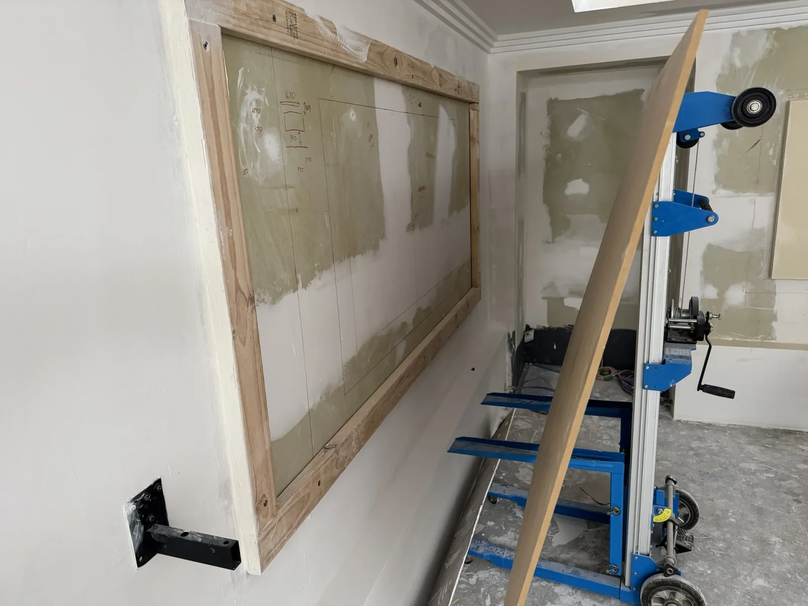 A panel lift holding plasterboard against the wall frame.