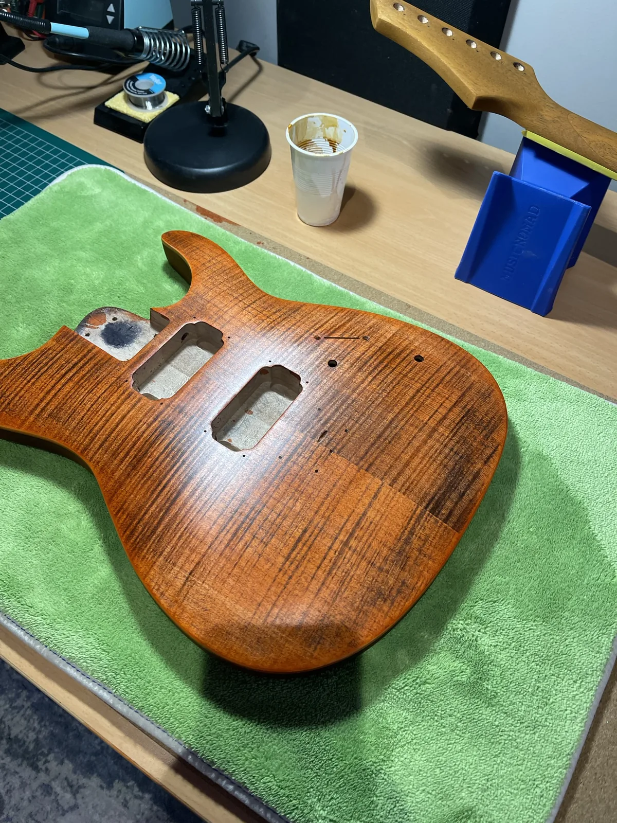 A freshly stained flame-maple guitar body drying on the bench.