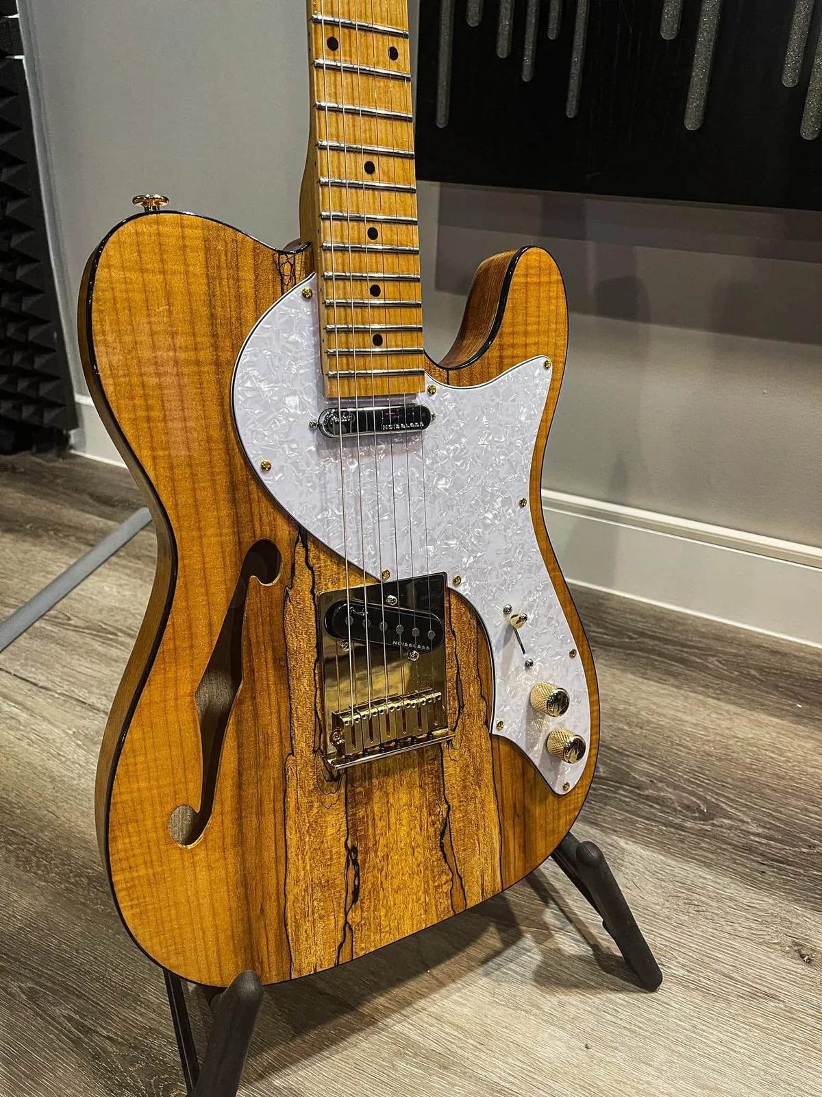 A spalted-maple thinline telecaster-style guitar on a stand.