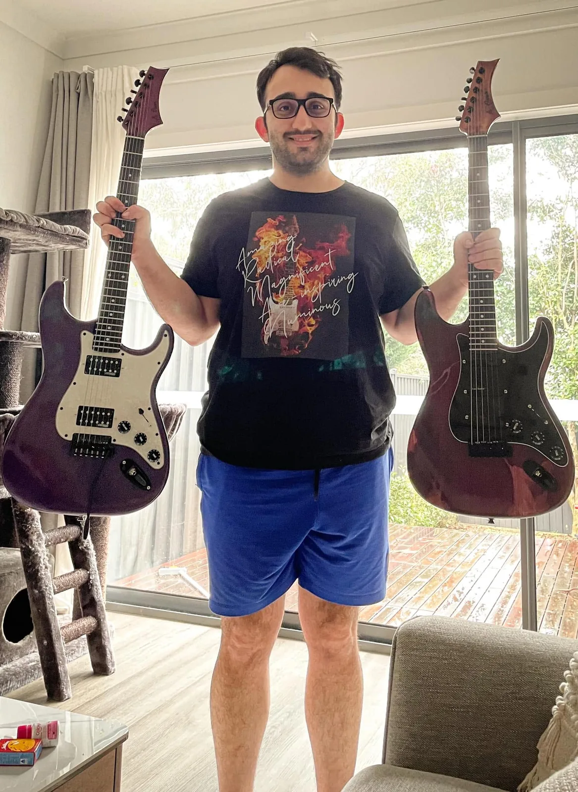 Arman holding two purple homemade guitars.