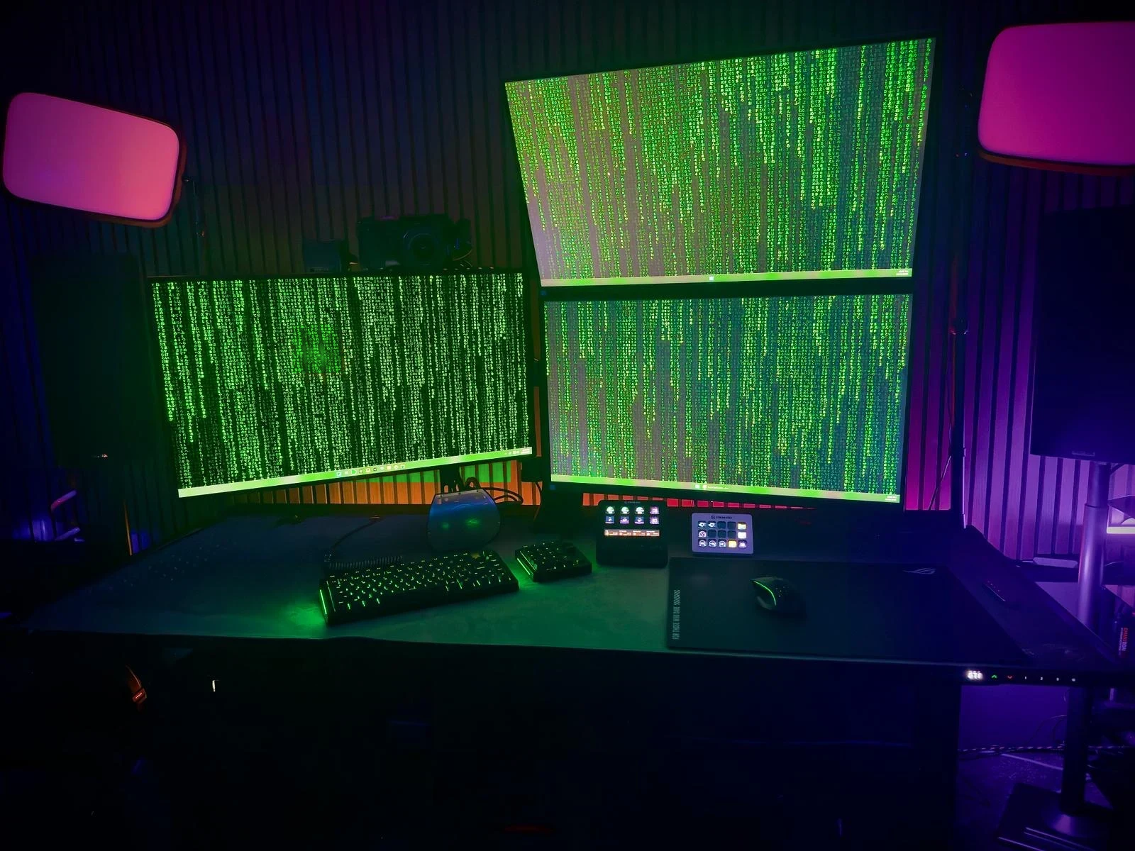 The lab after dark: three monitors of cascading green code in a purple-lit room